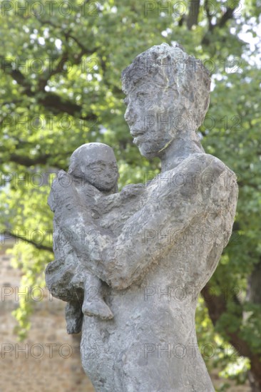 Sculpture Mother and Child by Sabine Grzimek 1981, bronze sculpture, life-size, modern art, standing female figure carrying infant in her arms, infant, protect, relationship, care, detail, sculpture park, Magdeburg, Saxony-Anhalt, Germany