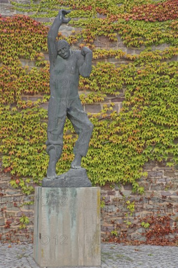 Sculpture Ascending man by Fritz Cremer 1967, rising man figure, arms, up, gesture, upwards, climb, move, rise, bronze sculpture, modern art, life-size, wall, ivy, vines, autumn, sculpture park, Magdeburg, Saxony-Anhalt, Germany