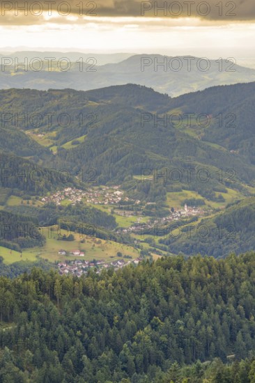 Village nestled in green hills and forests under a cloudy sky, Black Forest, Seebach, Germany