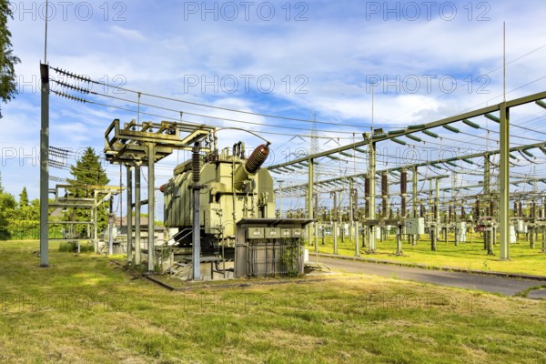 Left large transformer transformer transformer power transformer in substation, right hanging suspended power lines for transmission of electrical energy power supply, Germany