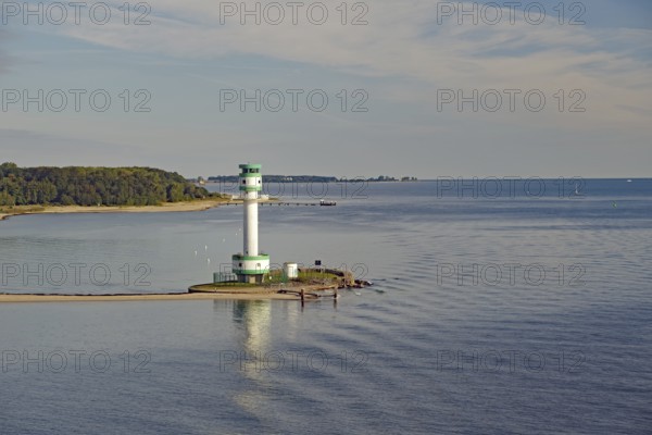 A lighthouse stands on a small headland in the calm sea under a slightly cloudy sky, Kiel Fjord, Kiel, Schleswig-Holstein, Germany