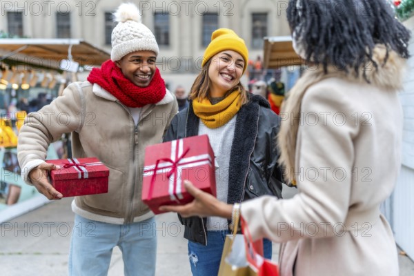 Happy friends exchanging christmas gifts at a bustling market, enjoying the festive atmosphere and celebrating the joy of the season
