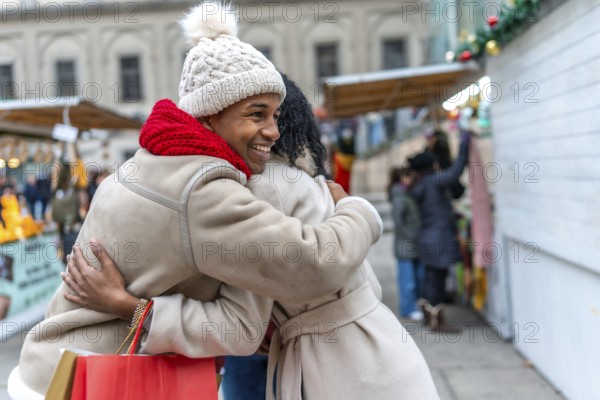 Two happy friends are hugging at a christmas market in a winter city, enjoying the festive atmosphere and holiday shopping
