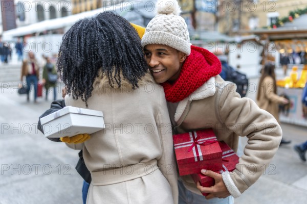 Two friends joyfully exchanging gifts at a bustling outdoor christmas market, surrounded by festive decorations and the warmth of holiday spirit