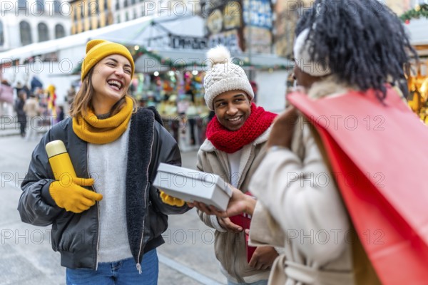 Happy multi ethnic friends joyfully exchanging christmas gifts at a bustling winter market, surrounded by festive lights and decorations
