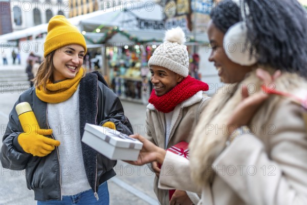 Happy multi ethnic friends exchanging christmas presents at a winter street market, enjoying the festive atmosphere