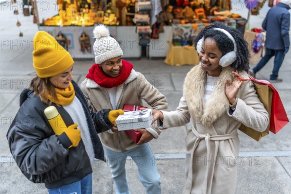 Happy multi ethnic friends exchanging christmas gifts at the christmas market during wintertime