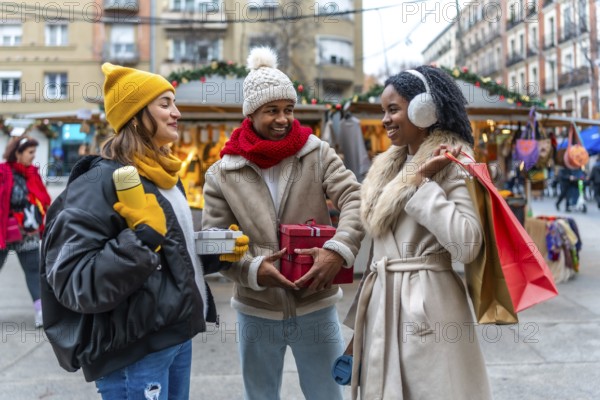 Happy multi ethnic friends exchanging christmas gifts while enjoying a stroll through a winter street market