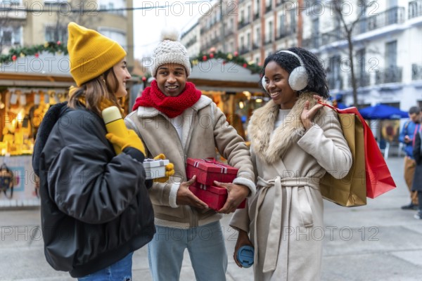 Three friends exchanging christmas gifts and enjoying a warm beverage at a christmas market in the city