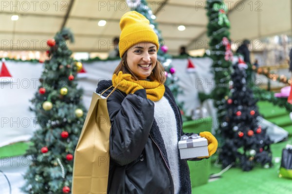Young woman holding christmas present and shopping bag, enjoying shopping at christmas market