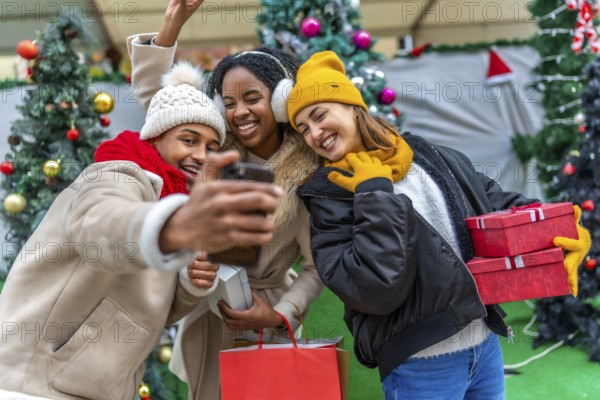 Happy multi ethnic friends taking a selfie after a christmas shopping spree, holding gifts and shopping bags
