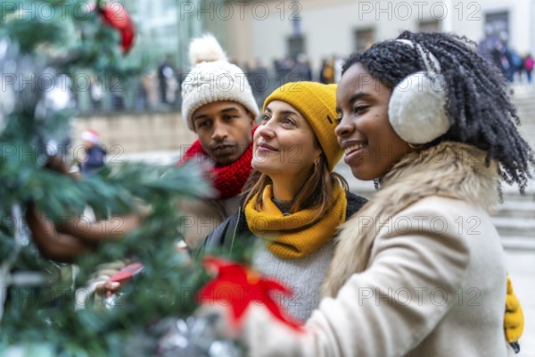 Three friends admiring christmas decorations on a city tree during winter holidays, enjoying time together