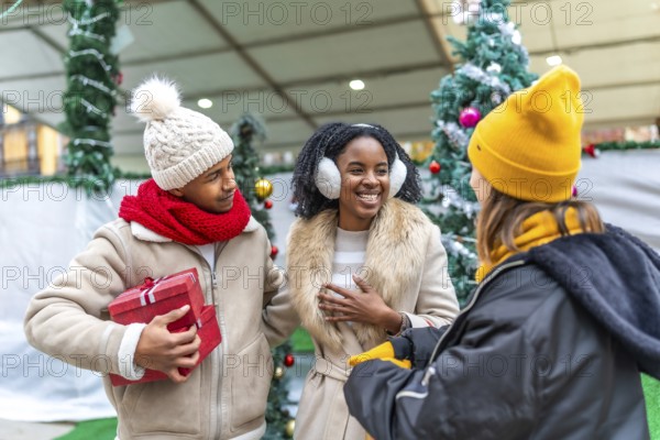 Happy friends exchanging gifts and enjoying christmas time together at a decorated christmas market