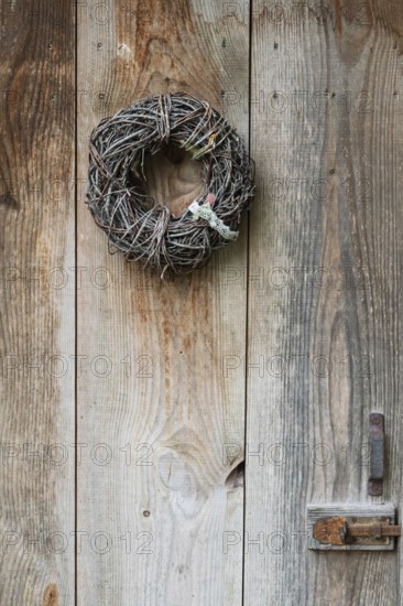 Door wreath made of natural materials in front of an old wooden door, North Rhine-Westphalia, Germany