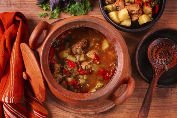 Chanakhi, a Georgian dish. in a clay pot, on a wooden table, stewed meat with vegetables, homemade, no people