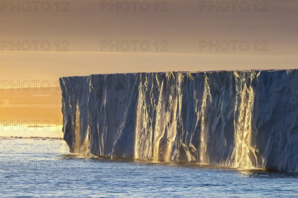 Waterfalls at edge of the Brasvellbreen glacier from ice cap Austfonna debouching into Barents Sea at sunset, Nordaustlandet, Svalbard, Spitsbergen