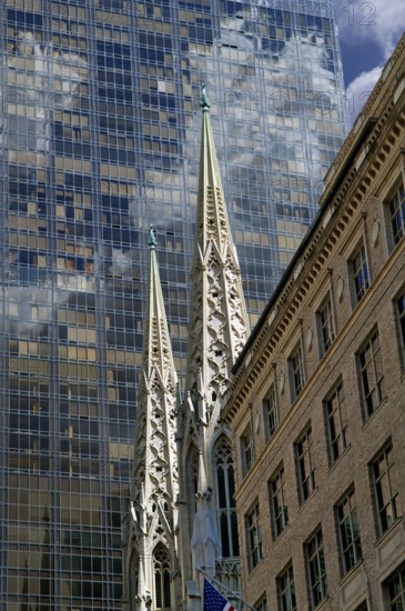 Towers of St Patrick's Cathedral in front of the facade of a skyscraper, Manhattan, New York City, USA