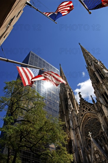 Towers of St Patrick's Cathedral in front of skyscrapers, waving US flags, New York City, USA
