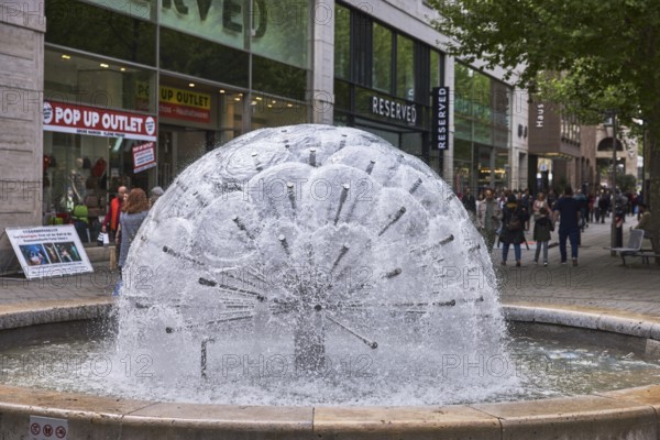 Dandelion fountain, frozen movement, water, stainless steel fountain, building, retail, shop window, trees, pedestrian zone, pedestrians as accessories, depth of field, diffuse light, Königstraße, Stuttgart, state capital, Stuttgart city district, Baden-Württemberg, Germany