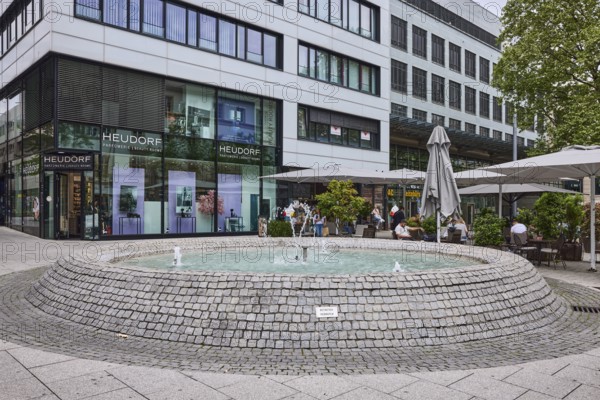 Cobblestone fountain, fountain, water, pedestrian zone, general architecture, shop window, outdoor area of a restaurant, sunshades, perfumery, facades, windows, cloudy, diffuse light, intersection Kronprinzstraße with Büchsenstraße, Stuttgart, state capital, Stuttgart city district, Baden-Württemberg, Germany