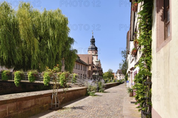 Ettlingen, Germany - August 13th 2025: Street in old historic city center with flower-covered bridge over Alb creek in Ettlingen