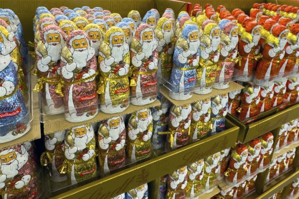 Display in shelf of wholesale of chocolate Father Christmases Father Christmases chocolate Father Christmases in different colours of staniol paper of chocolate brand Lindt arranged like army of Father Christmas, Germany