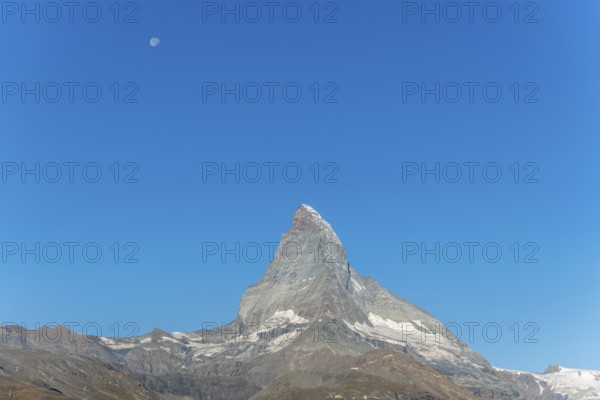 The iconic Matterhorn stands high above a clear evening sky illuminated by a bright moon. This breathtaking view captures the beauty and serenity of the Swiss Alps near Zermatt. Valais, Alps, Switzerland