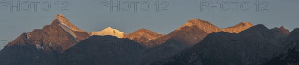 The mountain peaks glow with a soft orange light as the sun sets, creating a spectacular panorama. The beauty of the Alps is revealed under a clear sky. Grachen, Viege, Valais, Switzerland