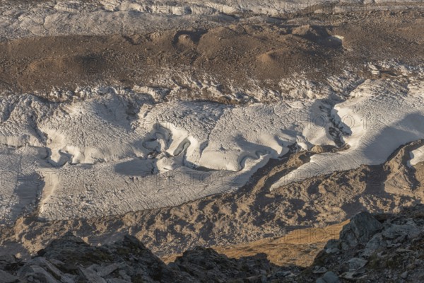 Detailed glacier formations stretch across the rocky landscape, revealing crevasses and structures, while the sunlight illuminates the scenery in the late afternoon. Gorner Glacier, Zermatt, Valais, Alps, Swiss