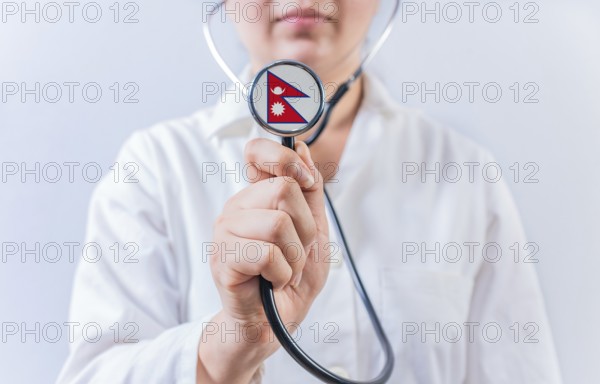 Female doctor holding stethoscope with Nepal flag. National health system of Nepal