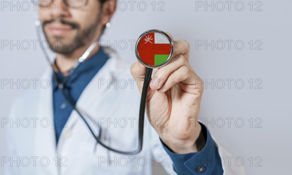 Doctor holding stethoscope with Oman flag. Oman health and care concept, Oman flag on stethoscope