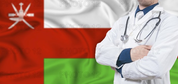 Oman healthcare concept. Male doctor on Oman flag. Doctor with crossed arms on Oman flag