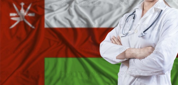 Doctor with crossed arms on Oman flag. Omani health and care concept. Female doctor on Oman flag