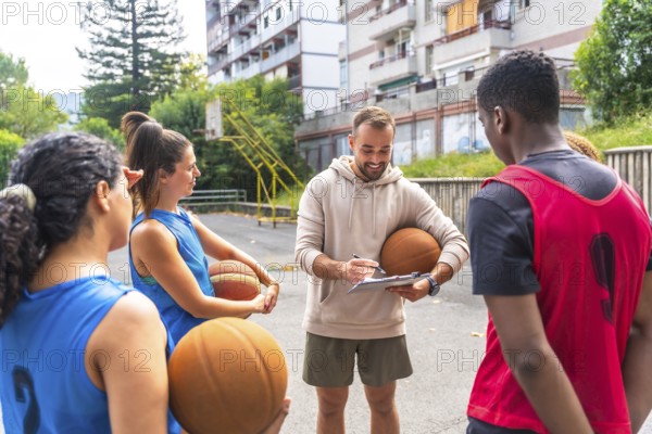 Basketball coach holding a ball and taking notes on a clipboard while engaging with team players on an outdoor court, emphasizing strategy and teamwork during practice sessions