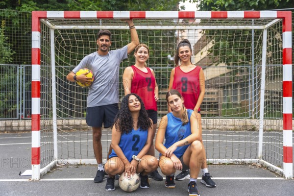 Five a side soccer team posing confidently with soccer balls in front of the goal, embodying teamwork and sportsmanship while preparing for a friendly match on the field