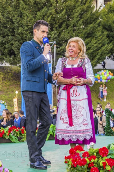 Bavarian Radio presenter Dominik Göbl in conversation with Elisabeth Polaczy, head of the historic Wiesn attraction Teufelsrad, Wiesnwirte Platzkonzert, Festwiese, Theresienwiese, Oktoberfest, Munich, Upper Bavaria, Bavaria, Germany