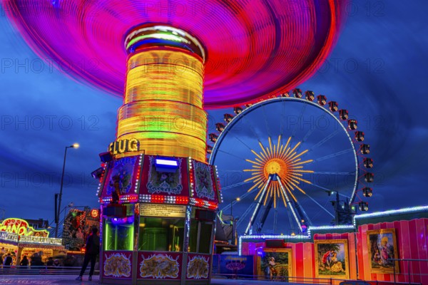 Illuminated chain carousel in motion, behind the Ferris wheel at standstill, Festwiese, Theresienwiese, Oktoberfest, Munich, Upper Bavaria, Bavaria, Germany