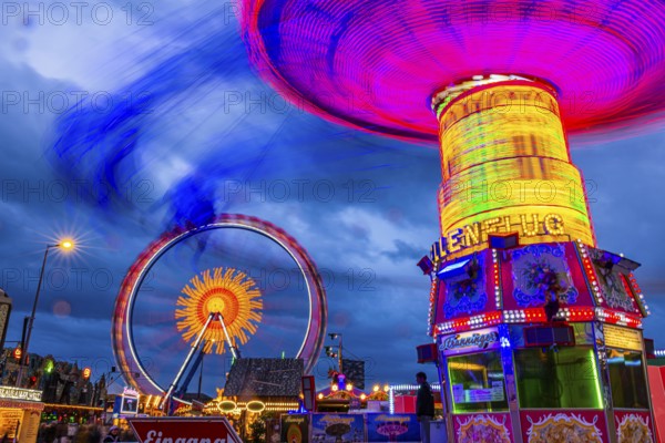 Illuminated chain carousel in motion, behind the Ferris wheel in motion, Festwiese, Theresienwiese, Oktoberfest, Munich, Upper Bavaria, Bavaria, Germany