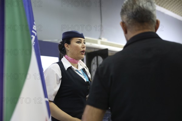 A flight attendant from Syrian Airlines speaks with visitors at the Damascus International Fair. The airline's pavilion featured presentations highlighting the company's services and role in the aviation sector, Damascus, Damascus, Syria