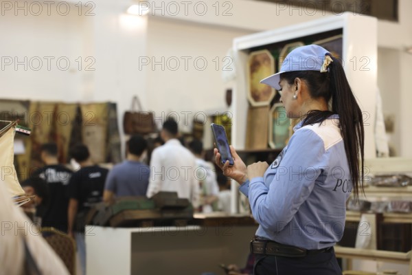 A female member of Syria's newly established tourist police stands inside the Damascus International Fair wearing a blue uniform. The tourist police force was formed after the fall of Assad's regime and deployed at the exhibition to interact with visitors and provide security services, Damascus, Damascus, Syria