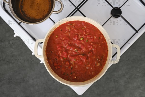 Overhead view of cooking tomato and bread soup on a stove