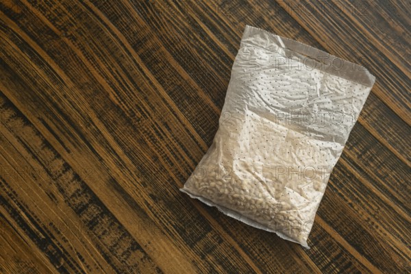 A sachet containing pearl barley is placed on a wooden kitchen table. It is ready for cooking, showcasing the natural beauty of this versatile grain typically used in healthy meals