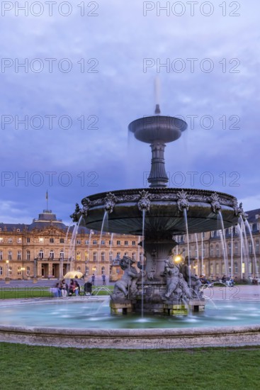 Evening atmosphere at Schlossplatz Stuttgart. View of the New Palace. Illuminated fountain bowl at the fountain. Stuttgart, Baden-Württemberg, Germany