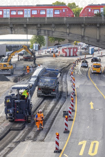 Surfacing work on the B10 federal road at the Leuze junction. A construction machine mills asphalt from the road. S-Bahn on a railway bridge. Stuttgart, Baden-Württemberg, Germany