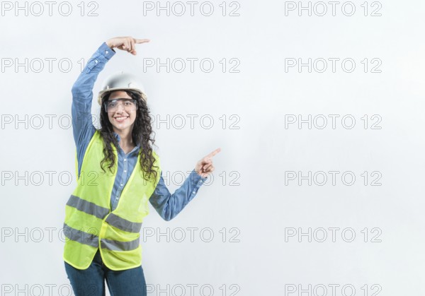 Smiling female builder pointing an advertisement isolated. Beautiful female engineer pointing to the side with both fingers isolated