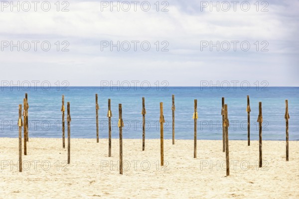 Parasol poles on a empty sandy beach by the Mediterranean sea with a seascape view to the horizon, Mallorca, Spain