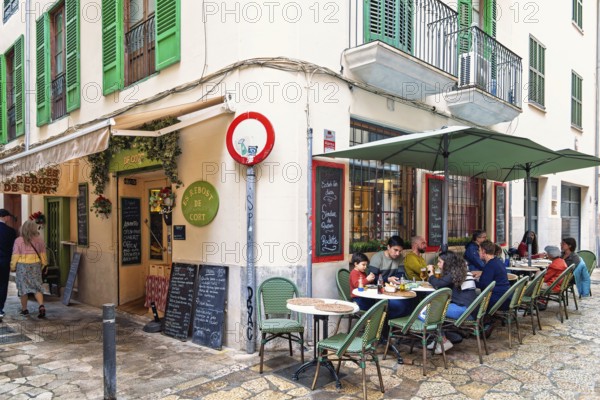 Food restaurant with people sitting at tables by a street in the old town of Palma, Palma de mallorca, Mallorca, Spain