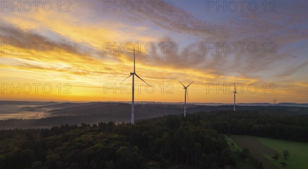 Wind turbines above a rich forest landscape at sunrise with a yellow pastel sky, near Schorndorf, Rems-Murr district, Rems-Murr-Kreis, Baden-Württemberg, Germany