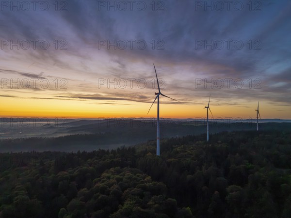 Three wind turbines on a green hill at sunrise with sweeping mountain views, near Schorndorf, Rems-Murr district, Rems-Murr-Kreis, Baden-Württemberg, Germany