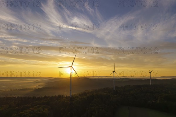 Wind turbines rise in front of a sunrise over a green landscape, creating a tranquil atmosphere, near Schorndorf, Rems-Murr district, Rems-Murr-Kreis, Baden-Württemberg, Germany